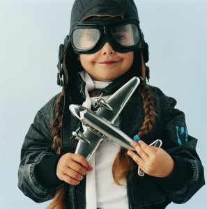 Young Girl in an Aviator Costume Folding a Toy Aircraft